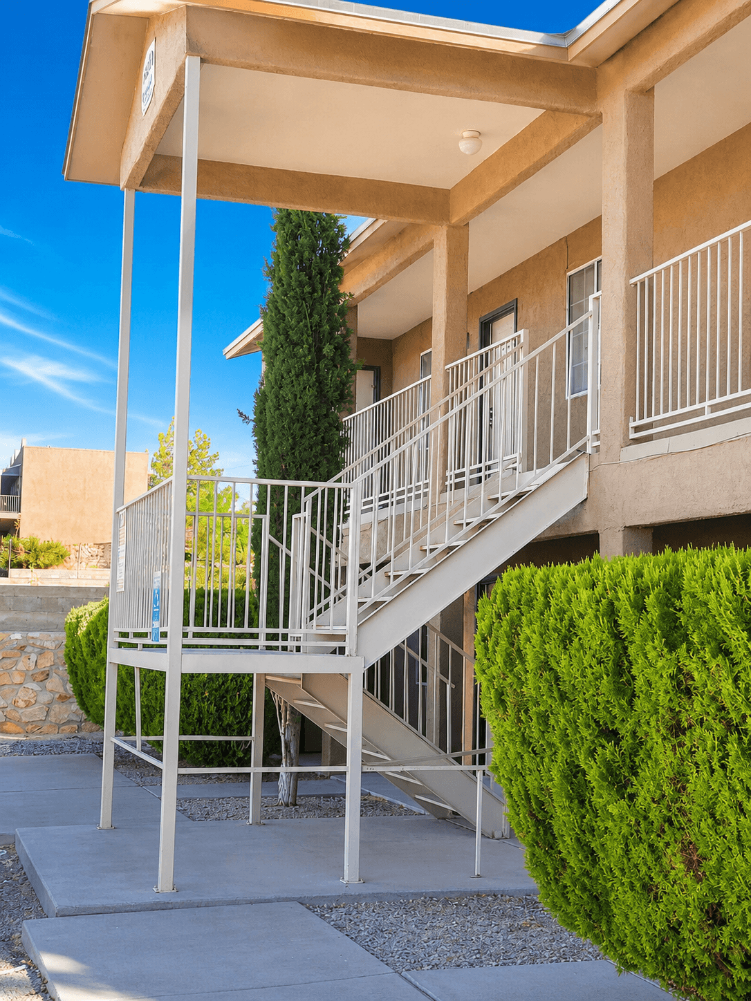 A staircase with a metal railing and a green bush on the side.